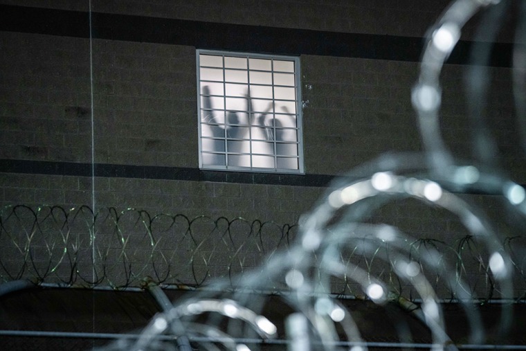 Detainees stand by a window inside the federal immigration center.