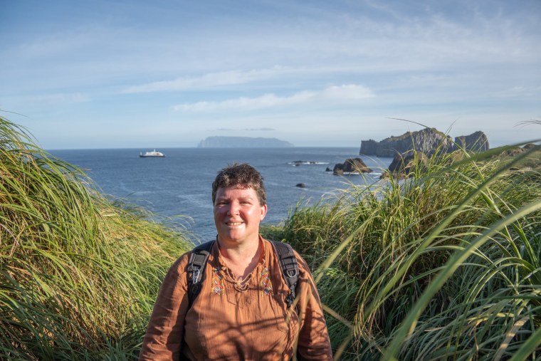 Angela Perryman stands outside near a cliff by the ocean